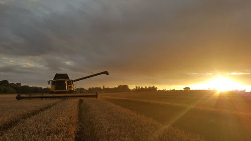 View of agricultural field against sky at sunset