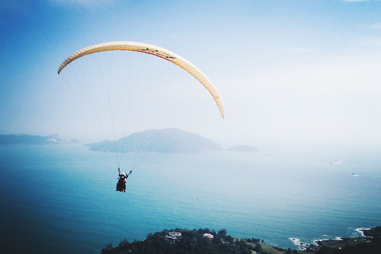 mountain, water, adventure, parachute, tranquil scene, scenics, tranquility, extreme sports, transportation, mid-air, paragliding, sea, flying, beauty in nature, one person, nature, sport, mountain range, leisure activity, waterfront