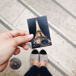 Low section of woman holding photograph with eiffel tower