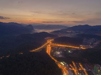 High angle view of illuminated mountains against sky at sunset