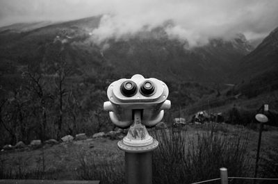 Close-up of coin-operated binoculars against mountains