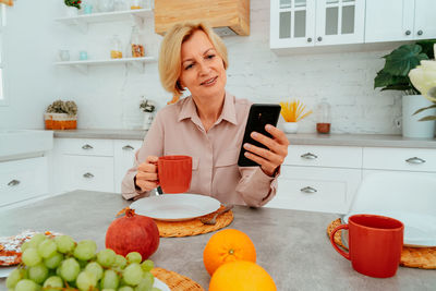 Young woman using phone while standing on table