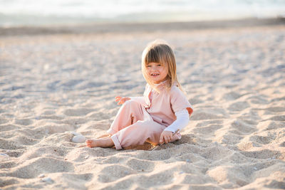 Pretty little child 2-3 year old playing at beach over sea at background in sun light outdoors. 