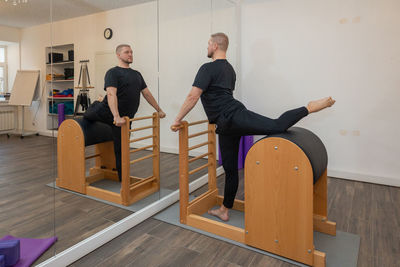 Male fitness pilates trainer shows exercises on special simulators. pilates stretch tables