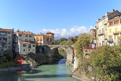 Bridge over dora baltea river in city against blue sky