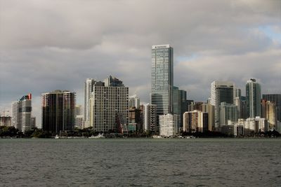 Sea by buildings against sky in city
