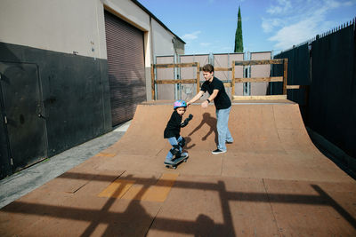 Skateboard instructor releases student on half pipe