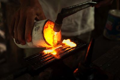 Midsection of manual worker heating metal in workshop