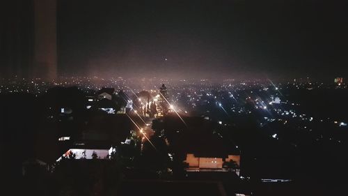 Illuminated cityscape against sky at night