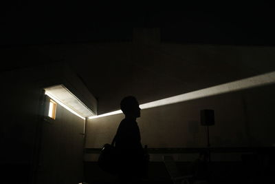 Silhouette man standing in illuminated room