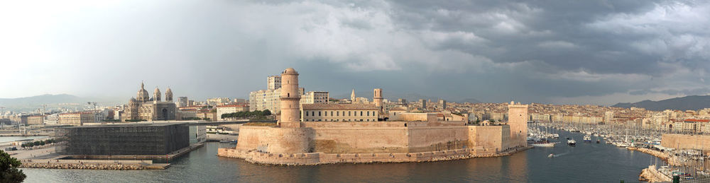 Panoramic view of buildings by river against sky in city