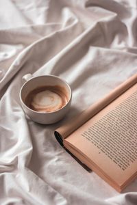 High angle view of coffee on the bed with old book