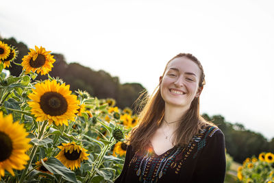 Portrait of smiling young woman against sunflower