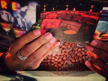 Cropped hands of woman holding photograph in restaurant