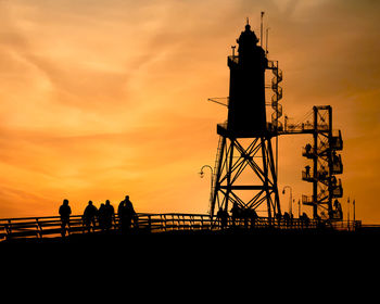 Silhouette people on bridge against sky during sunset