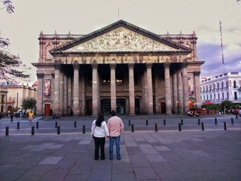 Rear view of couple standing against teatro degollado