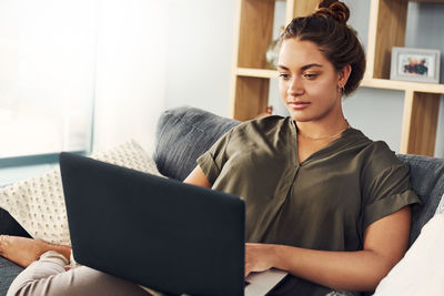 Woman using mobile phone while sitting on sofa at home