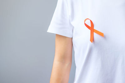 Midsection of man holding paper while standing against white background