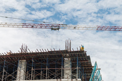 Low angle view of crane at construction site against sky