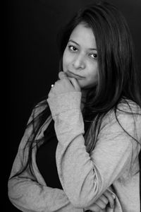 Portrait of beautiful young woman against black background