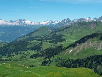 Scenic view of green landscape and mountains against sky
