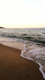 Scenic view of beach against clear sky during sunset