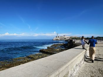 Rear view of man standing on jetty against sea