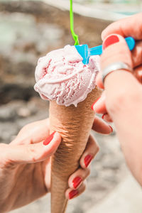 Cropped hand of woman holding ice cream cone outdoors