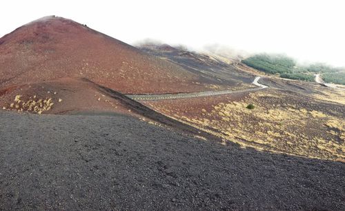 Scenic view of road by mountain against sky