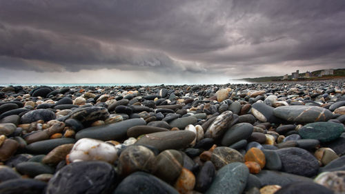 Surface level of pebbles at beach against sky during sunset