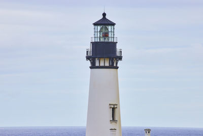 Lighthouse by sea against sky