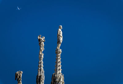 Low angle view of tall against clear blue sky