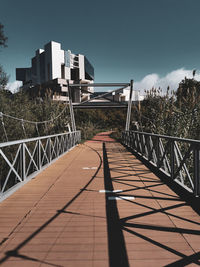 Footbridge over footpath against sky