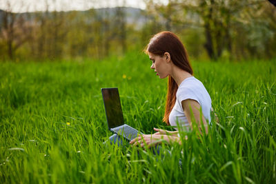 Young man using mobile phone while sitting on field