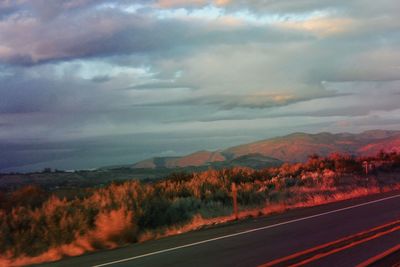Road by mountains against sky