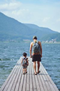 Rear view of people on pier against sky