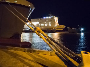 Illuminated ship moored at harbor against sky at night