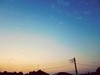 Low angle view of silhouette electricity pylon against sky during sunset