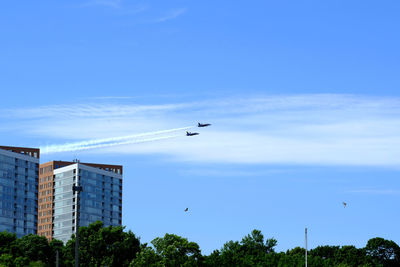 Low angle view of airplanes flying in sky over city