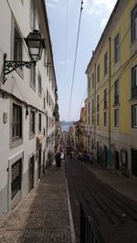 People walking on footpath amidst buildings in city