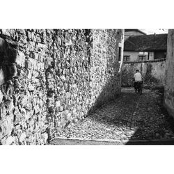 Rear view of man walking on alley amidst buildings