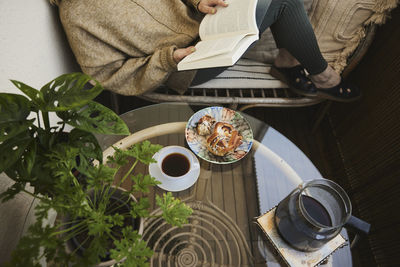 Woman reading book and having tea and snack