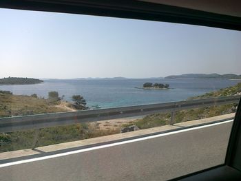 Road by sea against clear sky