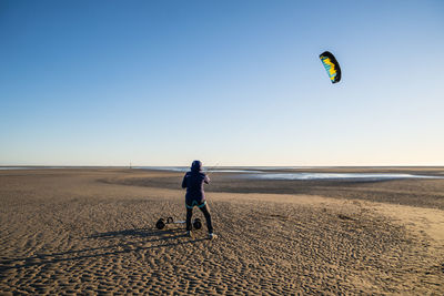 Man with umbrella on beach against clear sky