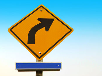 Low angle view of road sign against clear blue sky