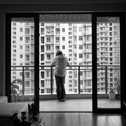 Rear view of man standing by window