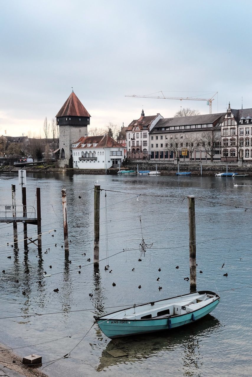 water, building exterior, architecture, nautical vessel, built structure, moored, boat, transportation, waterfront, sky, mode of transport, sea, harbor, house, river, reflection, pier, residential structure, day, outdoors