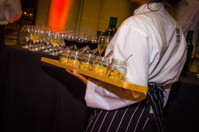 Midsection of waiter holding glass jars