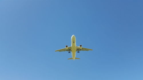 Low angle view of airplane against clear blue sky