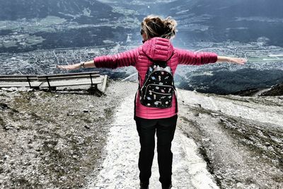 Rear view of woman with arms outstretched standing on mountain